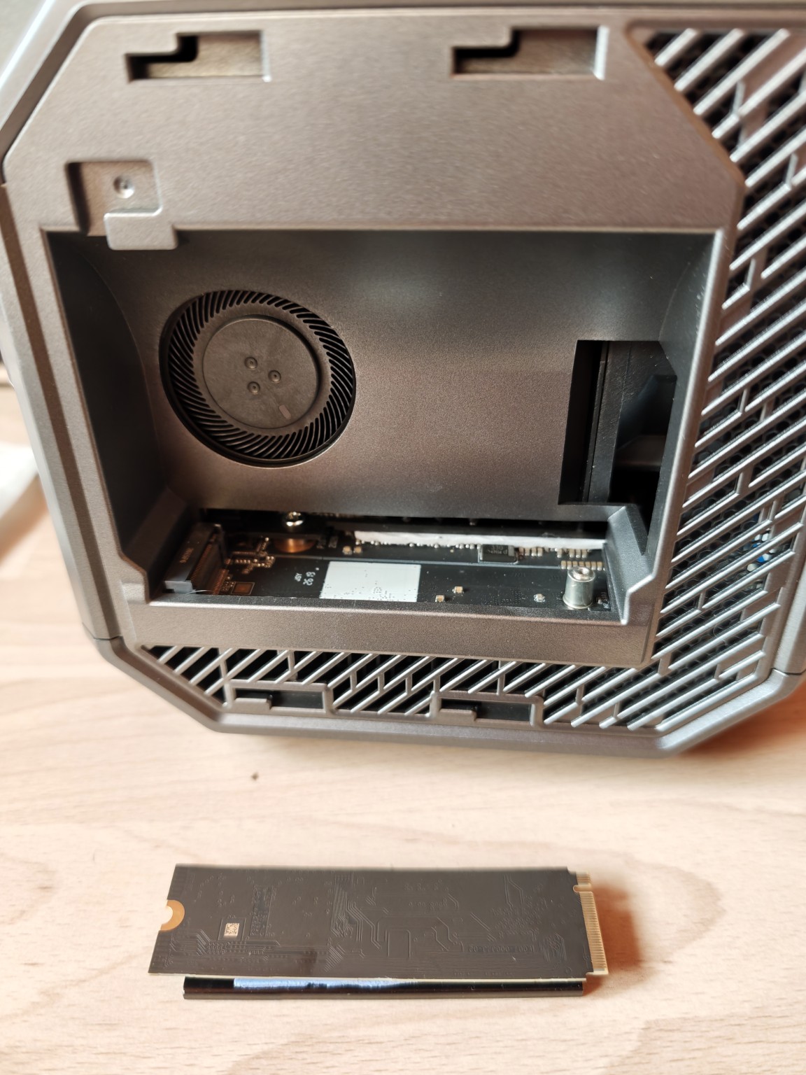 Compartimento del ACEMAGIC con una ranura M.2 bajo el ventilador y un SSD retirado sobre la mesa.